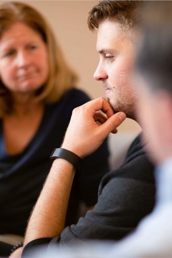 Young man thinking surrounded by his parents.