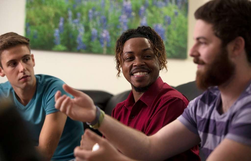 Young adult males having conversation at Rockville Sober Living house