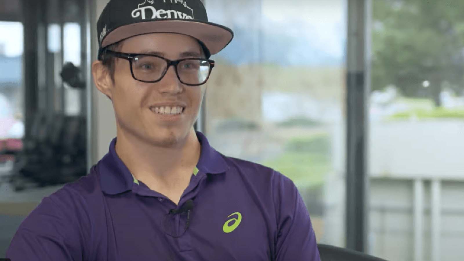 Young man with glasses smiling.