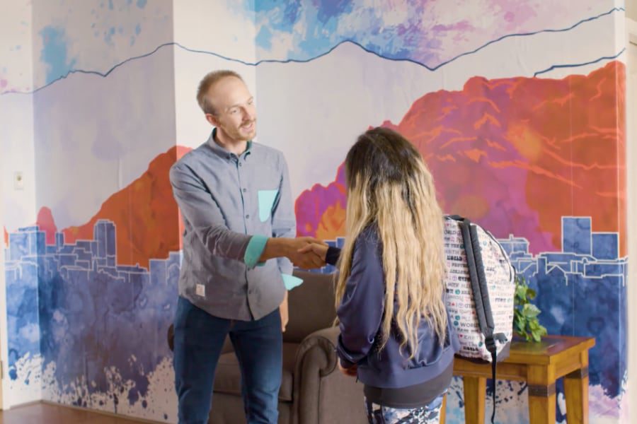 two people shaking hands in front of Sandstone Care Colorado Springs detox center mural