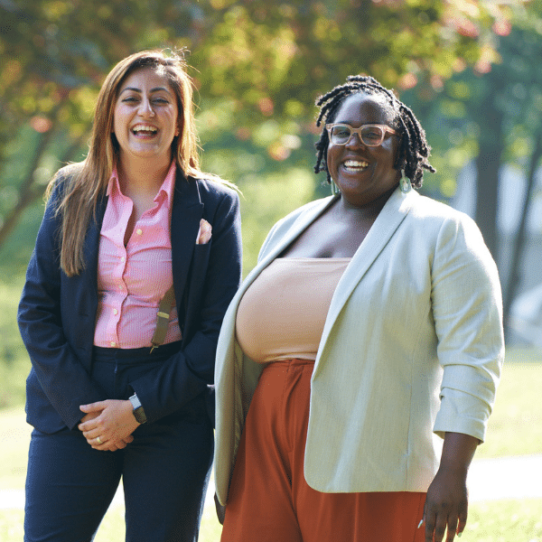 Two women clinicians laughing outside in nature.