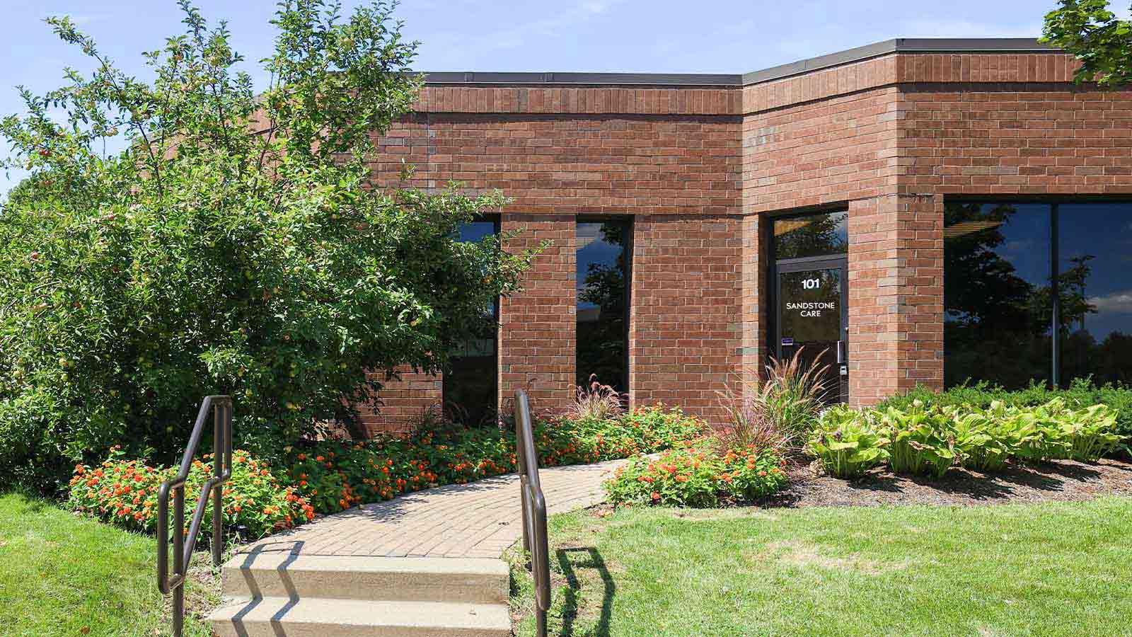 Exterior of a modern brick building with the door reading "Sandstone Care."