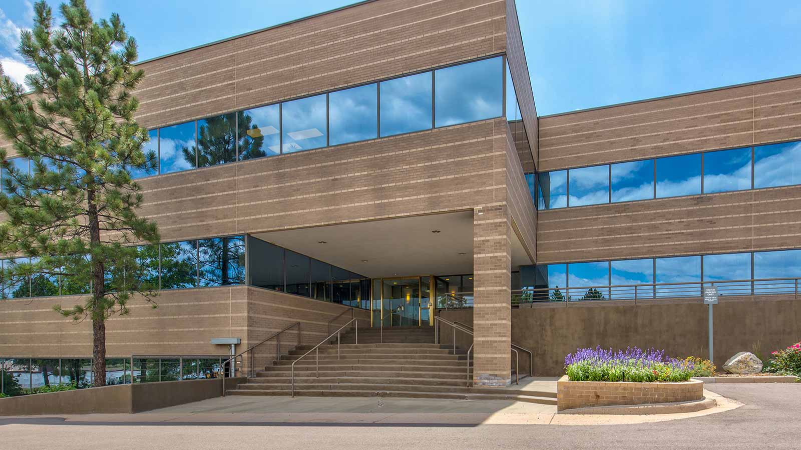 A multi-story building with a large overhang entrance and landscaped areas.