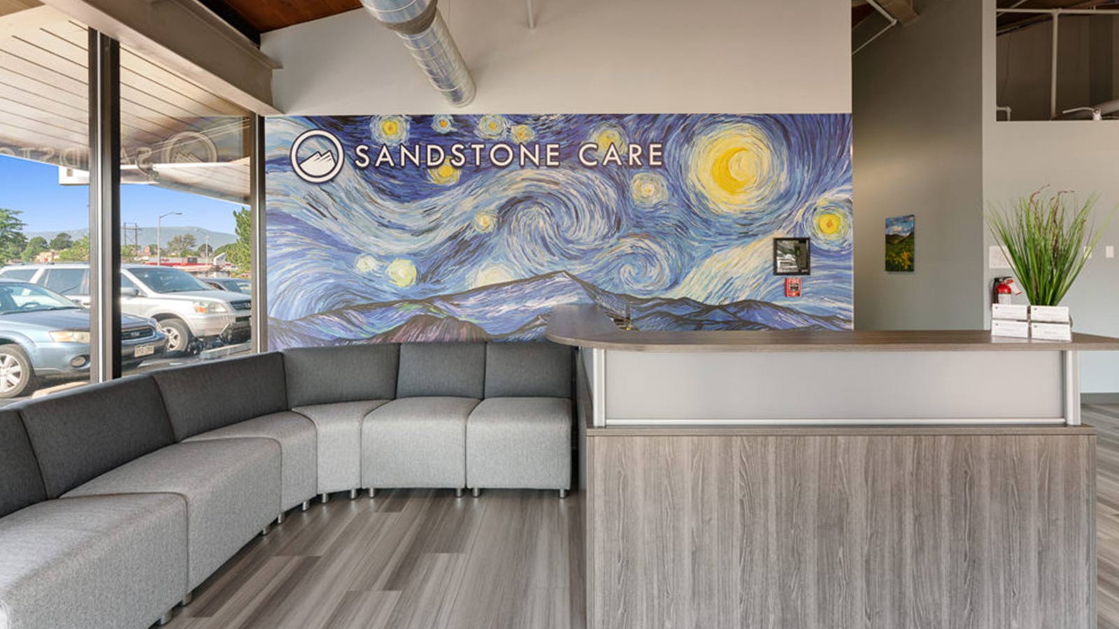 The reception area of a mental health center with a large, artistic mural and comfortable seating.