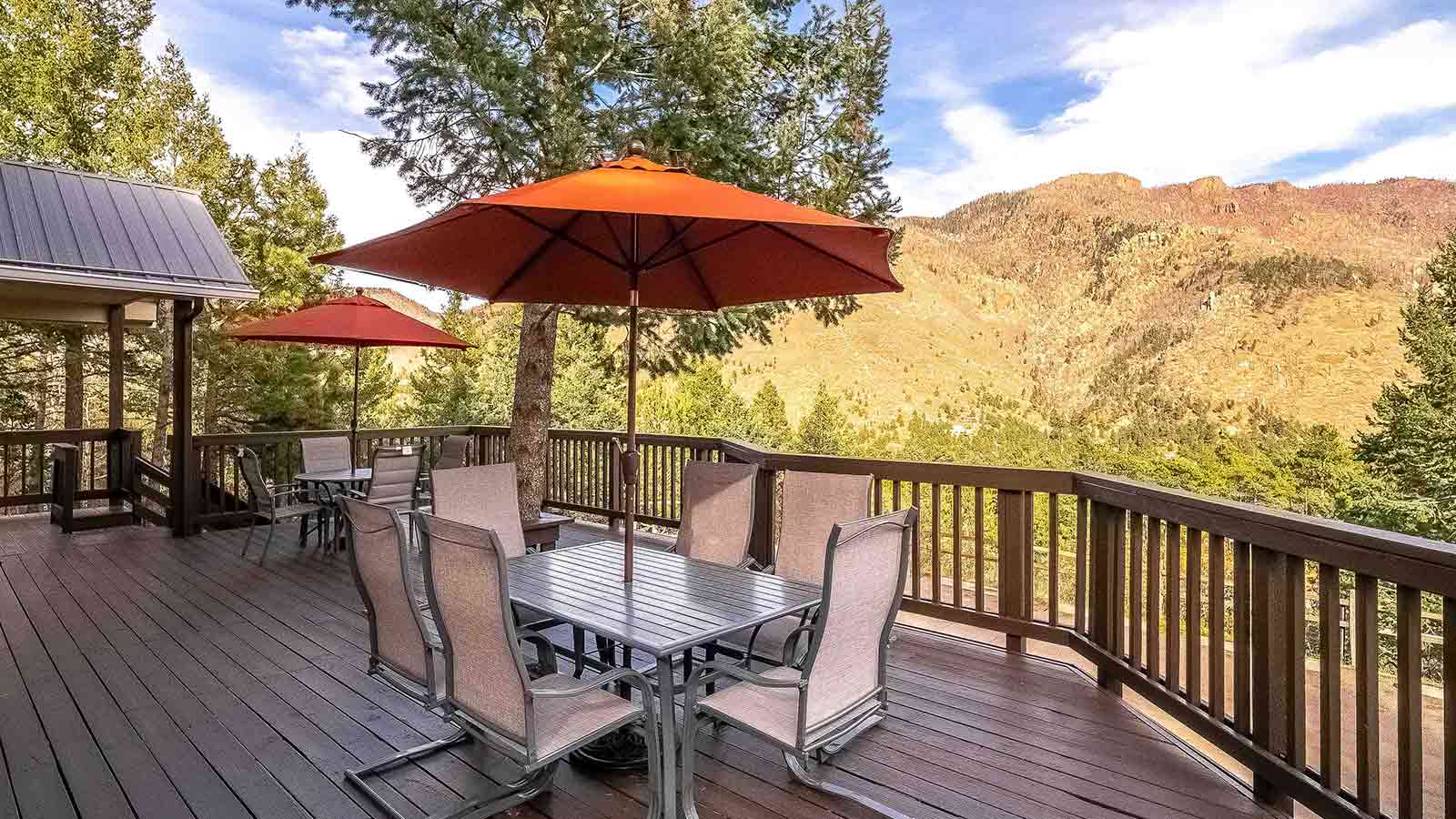 A deck with outdoor furniture overlooking a mountainous landscape.