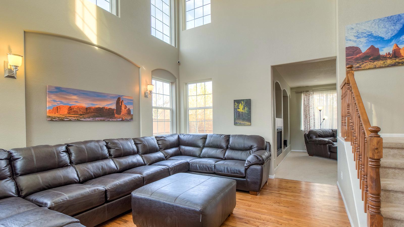 A spacious living room with a large leather sectional sofa and high ceilings.