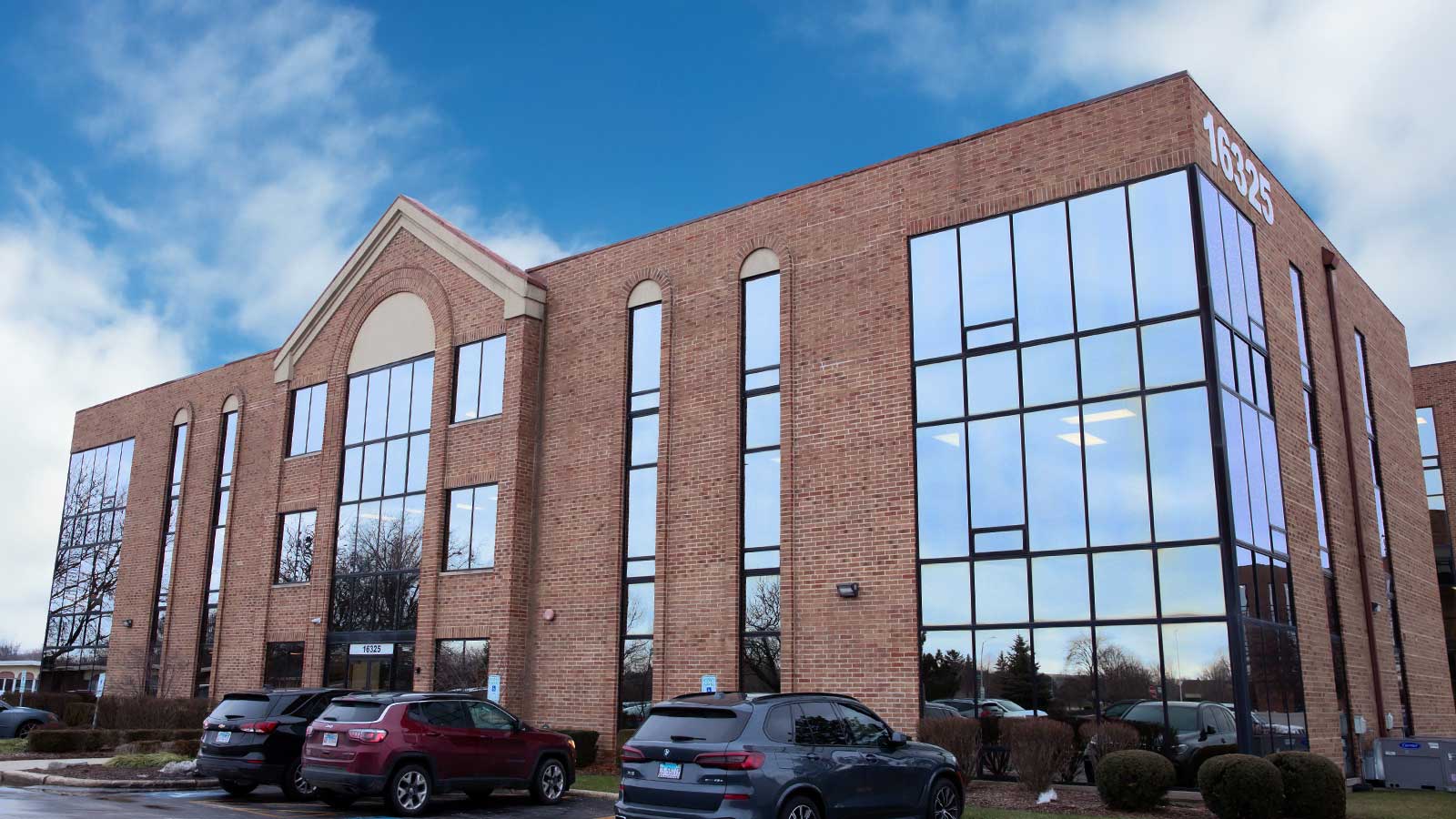 A two-story brick office building with large windows under a blue sky.