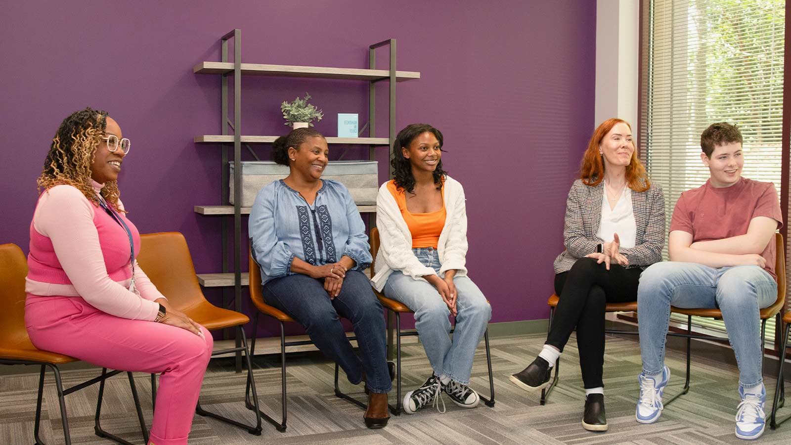 A group of teenagers and their parents in a group therapy session.