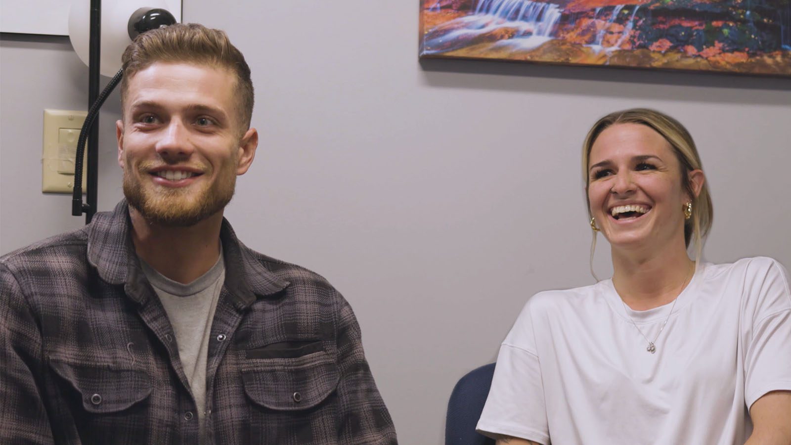 A male and female laughing together during a session in a room with colorful wall art.