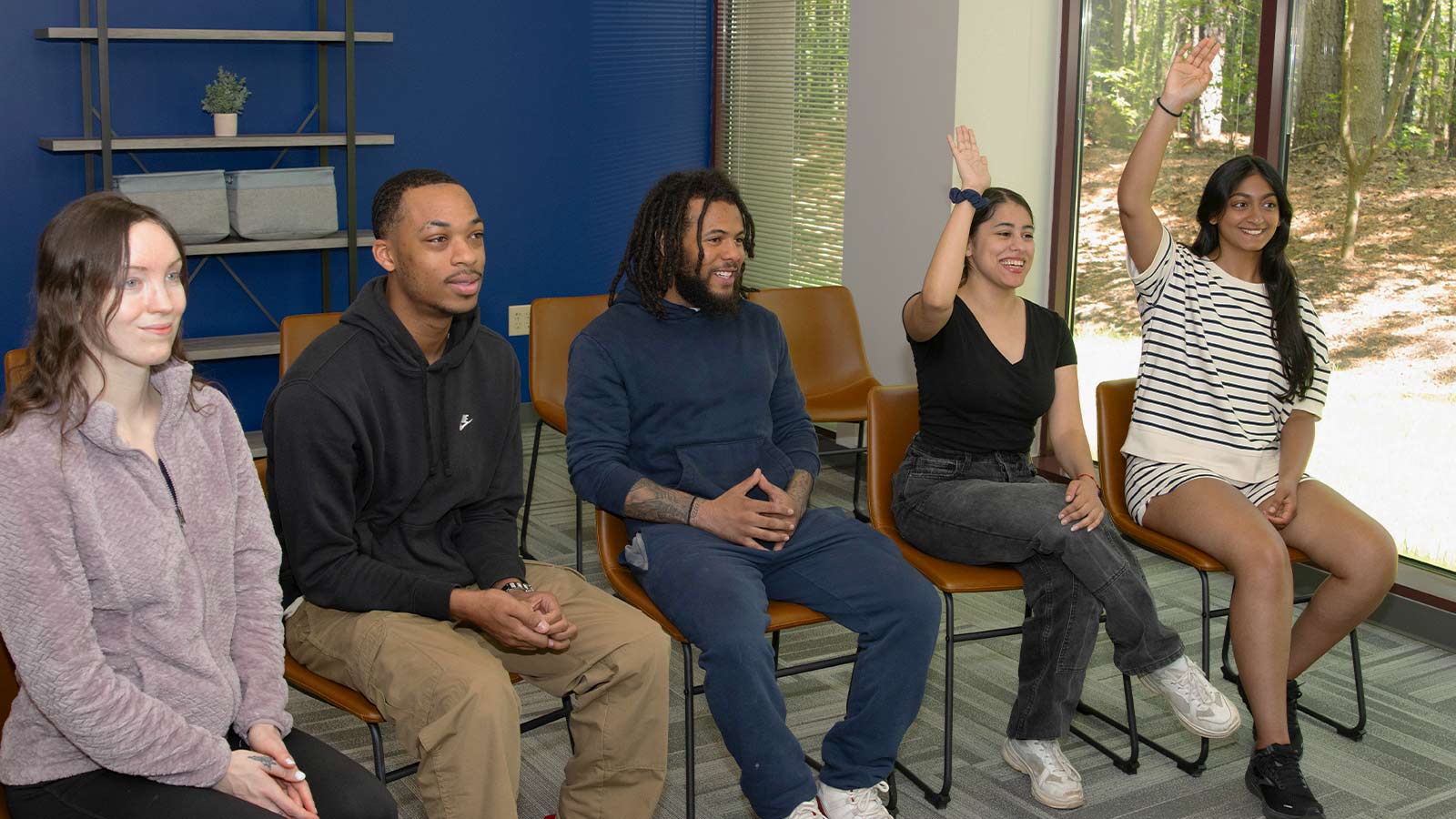 A group educational session with two people raising their hands.