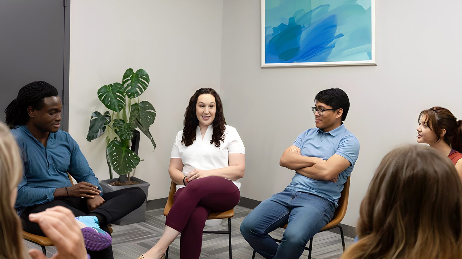 A group therapy session with five individuals seated in a circle, engaged in discussion.