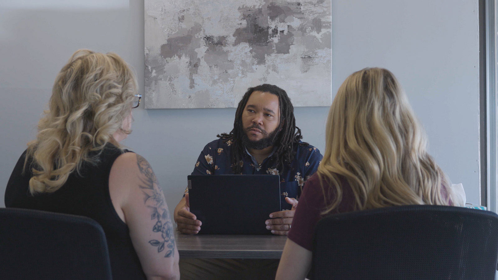 there are three people sitting at a table with a laptop