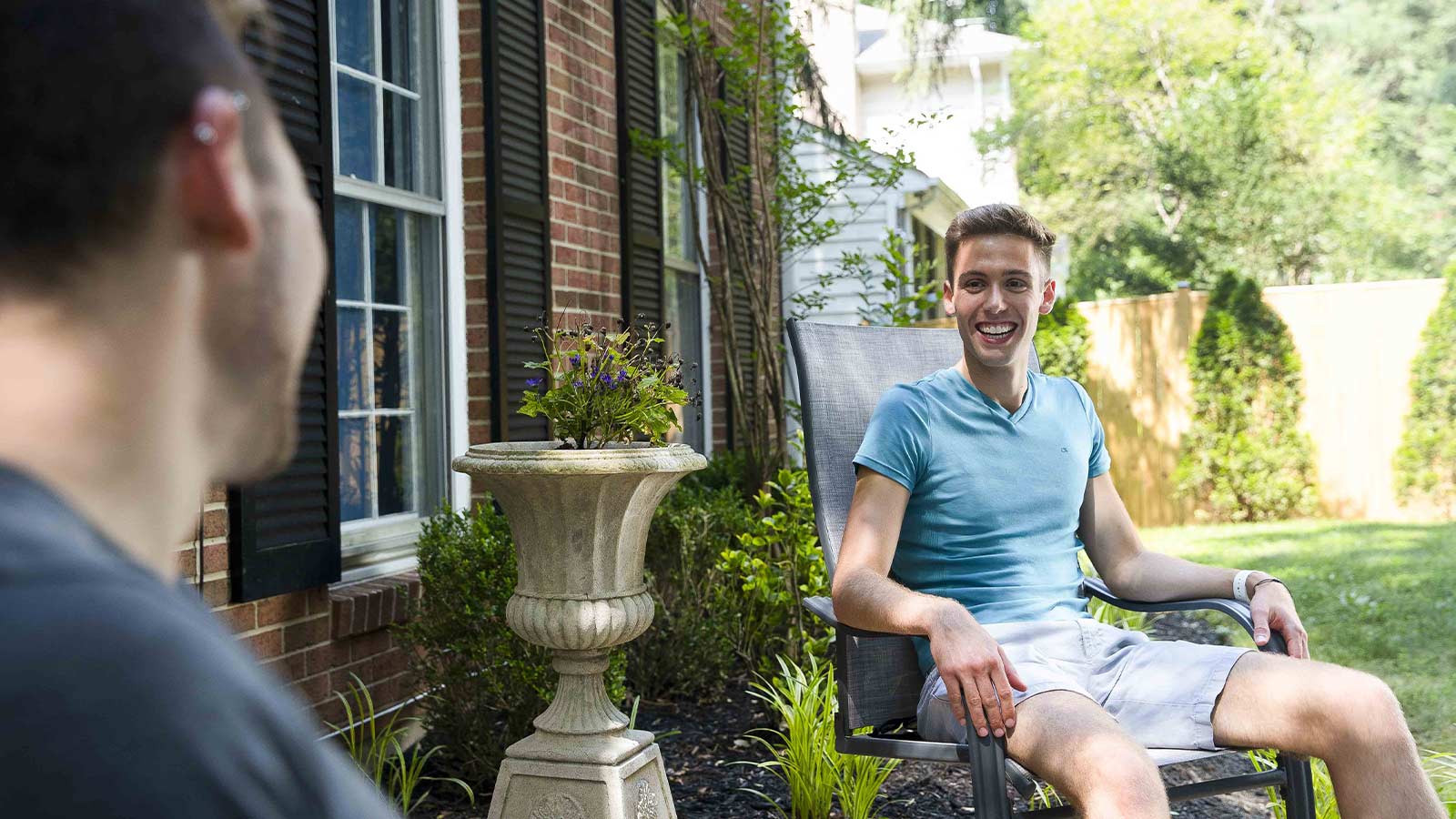 A smiling man sitting on a patio chair.