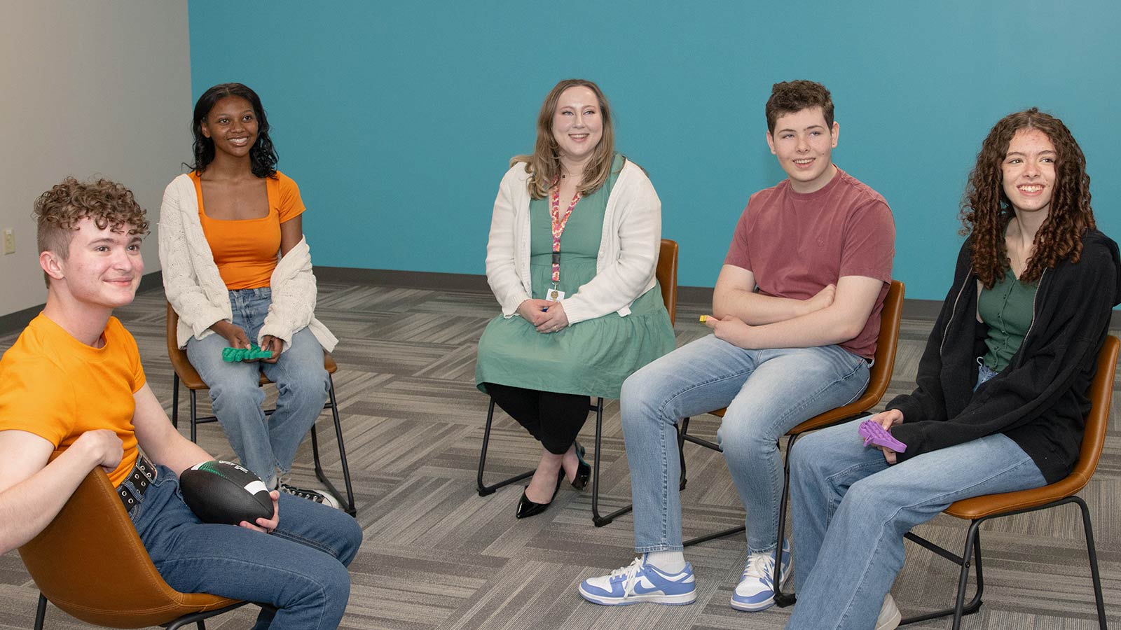 several people sitting in chairs in a room with a blue wall