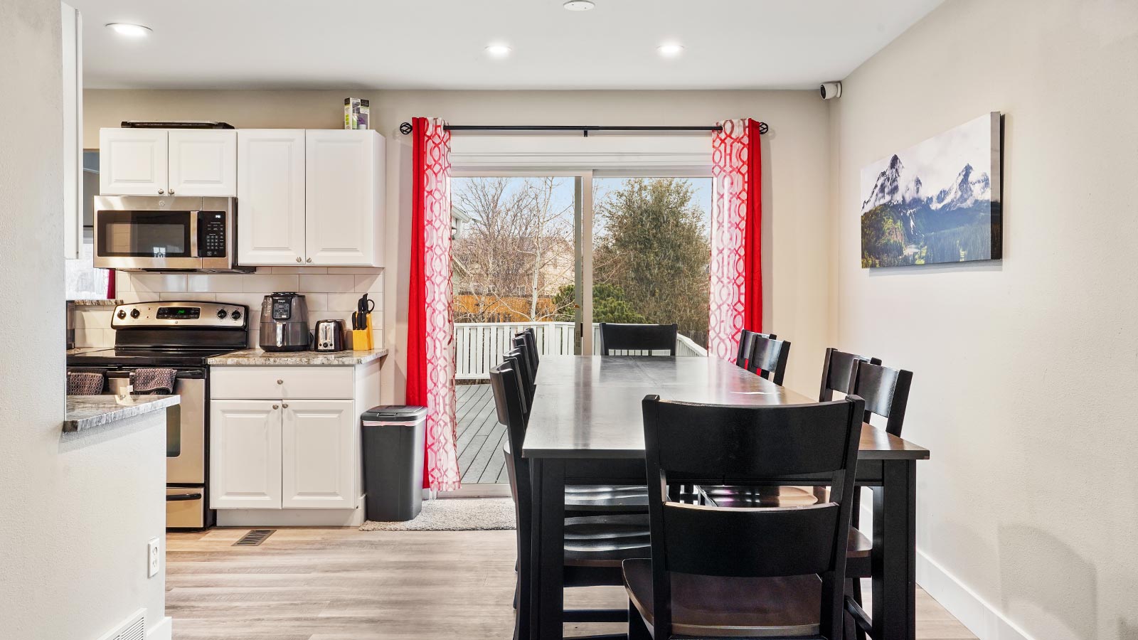 A bright kitchen with white cabinets and a dining area with a view of the backyard through sliding doors.