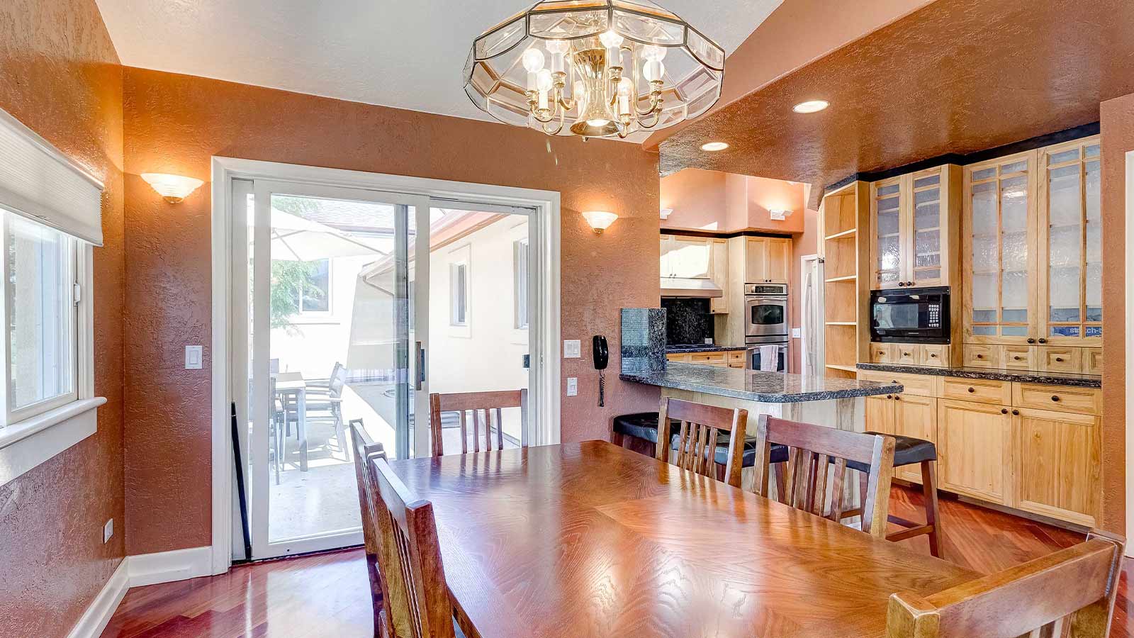 A spacious kitchen with wooden cabinetry and a large dining table set near sliding glass doors.