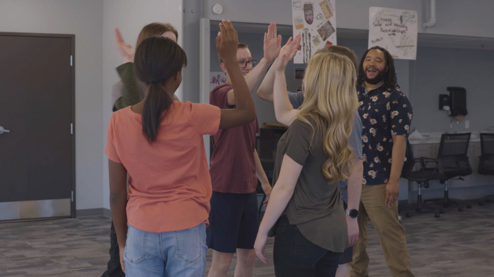 A group of teenagers giving high-fives to each other in a team-building exercise.