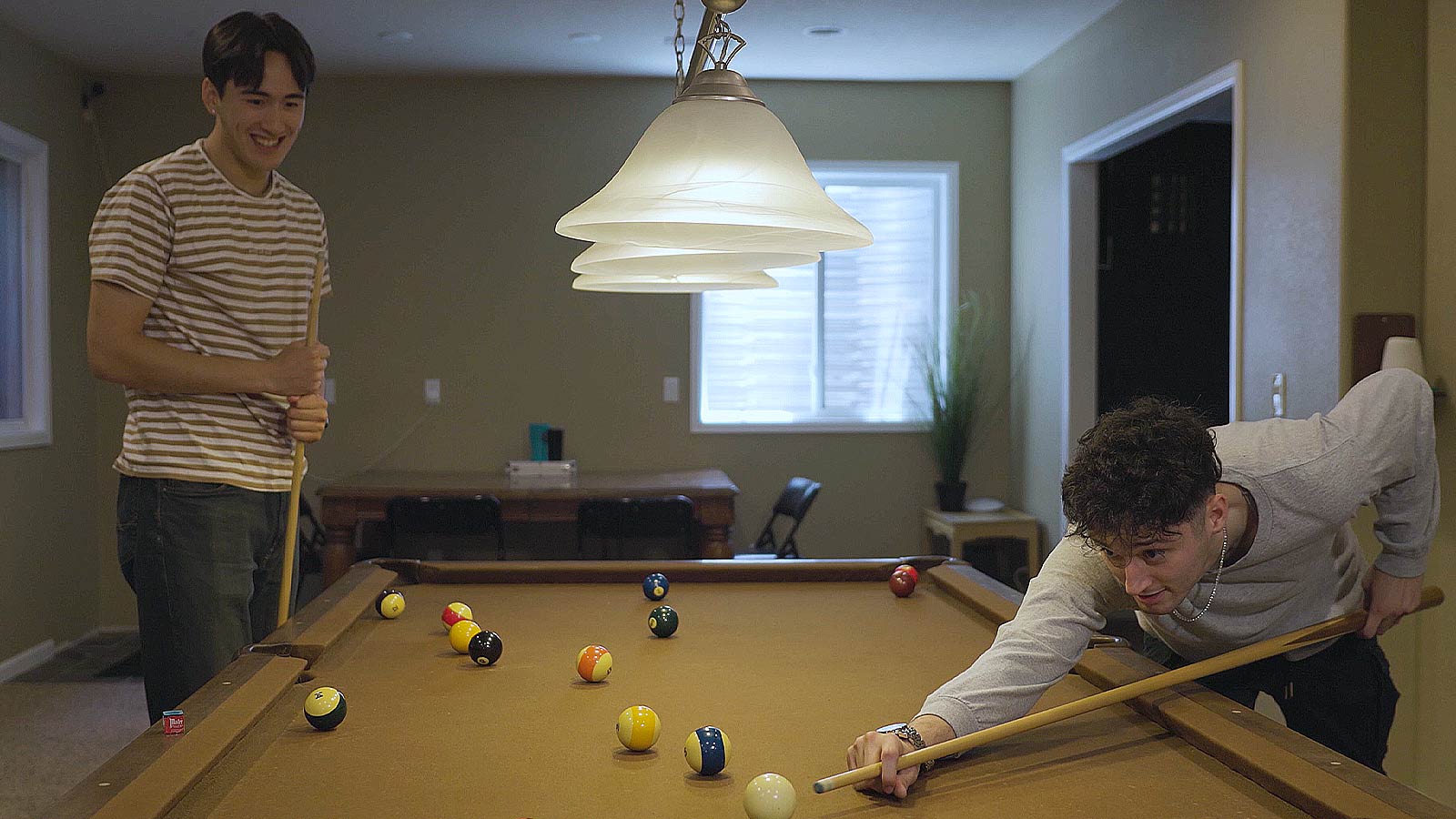 Two men playing a friendly game of billiards.