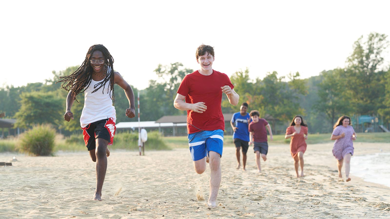 A group of young people joyfully running on a sandy beach.