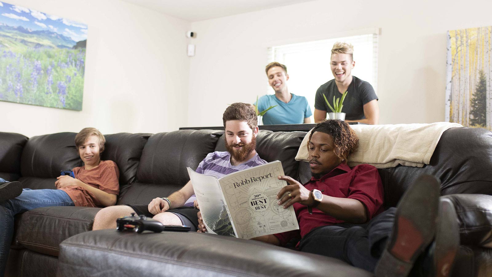 Four men enjoying each other's company in a living room, with one reading a newspaper.