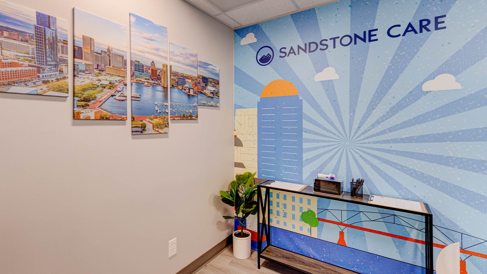 An interior wall decorated with a colorful mural and cityscape photographs, labeled "Sandstone Care."