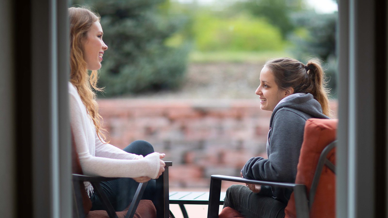 Two women enjoying a conversation over coffee on a quaint patio.