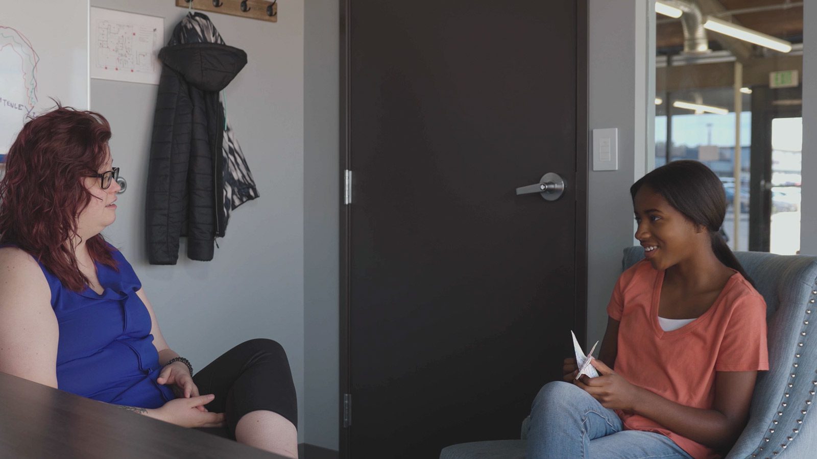 there are two women sitting at a table talking to each other