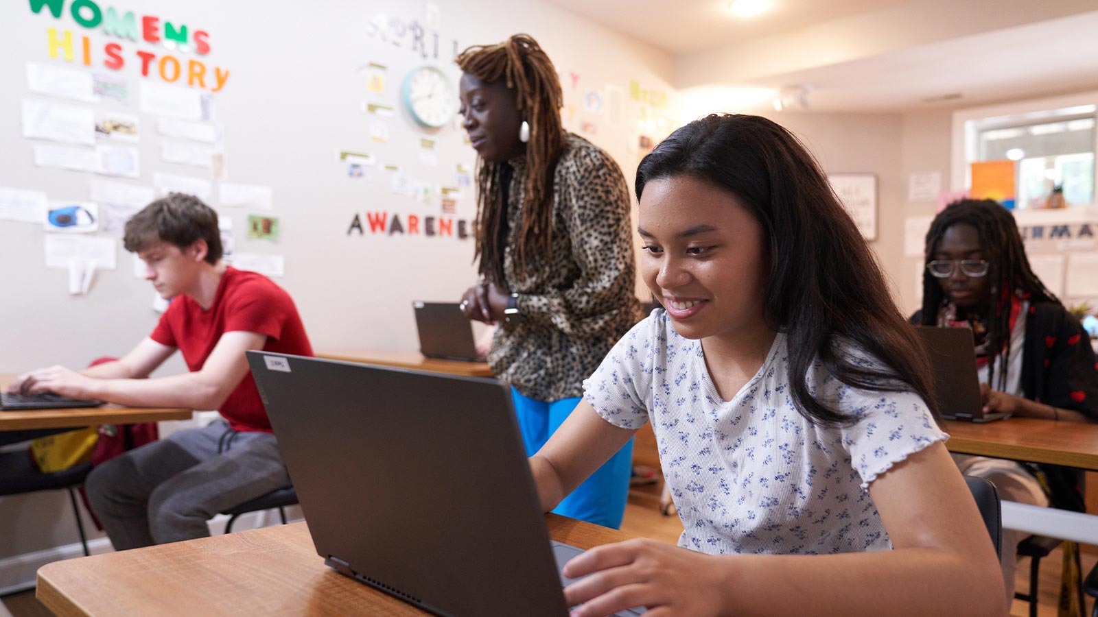 Students engaged in learning on computers in a classroom setting.