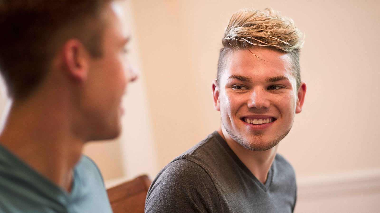 A close-up of two men having a friendly chat, one with a cheerful smile.