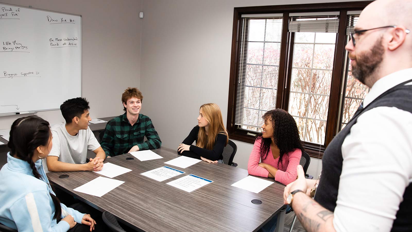 A group around a table listening to an educator.