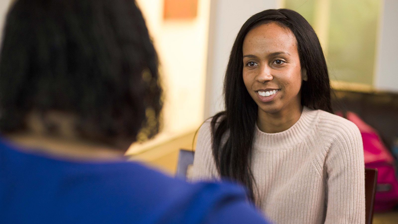 A smiling woman engaged in conversation with another individual.