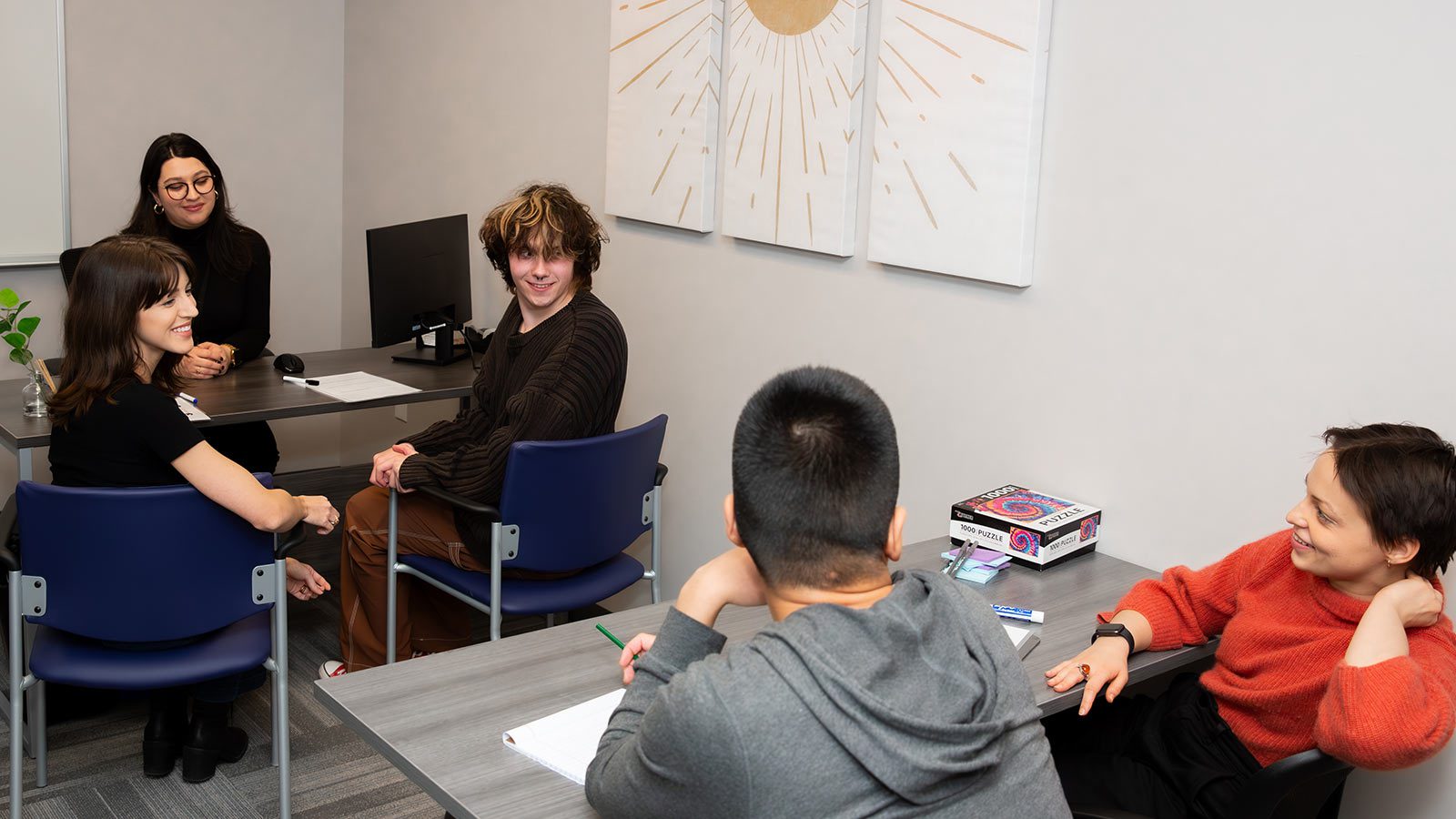 Four individuals and a teacher having lighthearted discussions.