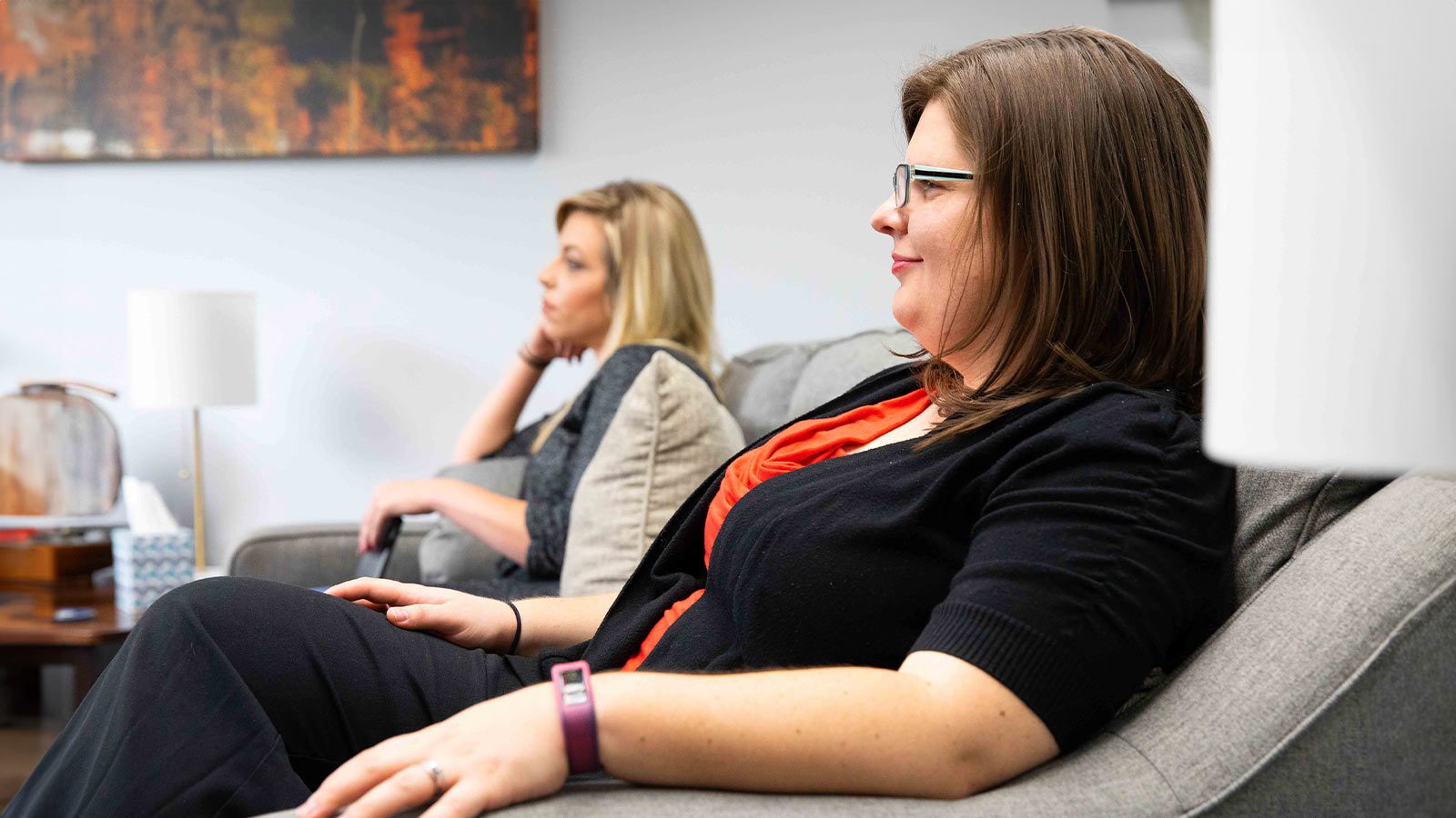 there are two women sitting on a couch in a room