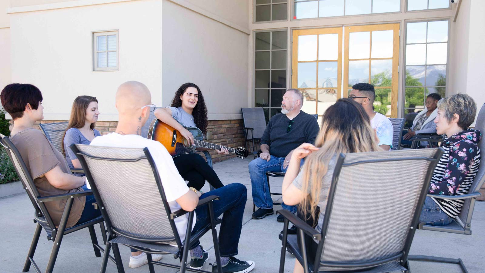 several people sitting in chairs talking to each other outside