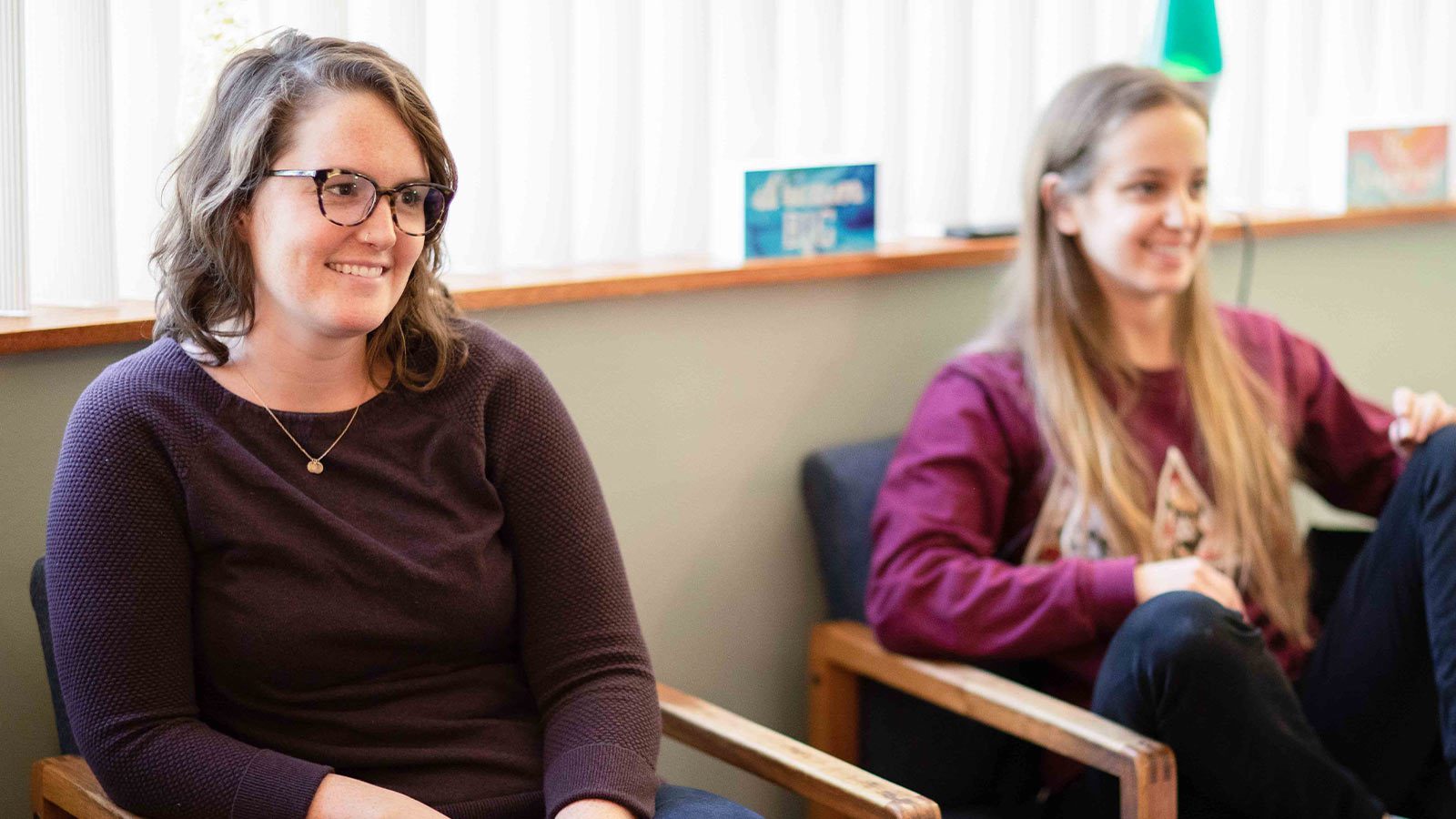 Two females engaged in conversation, seated comfortably in a warm, inviting room.