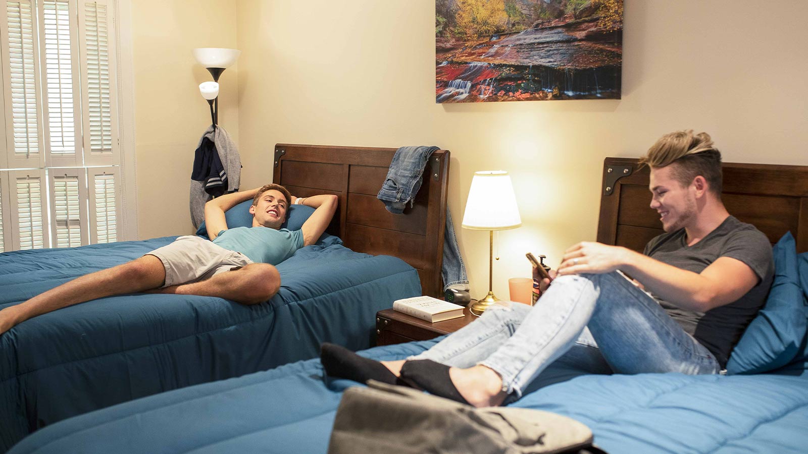 there are two men laying on the beds in a hotel room