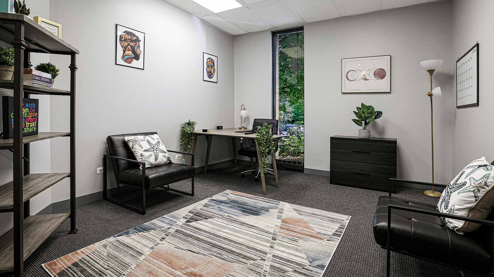 An inviting office space with a desk, comfortable seating, and decorative wall art.