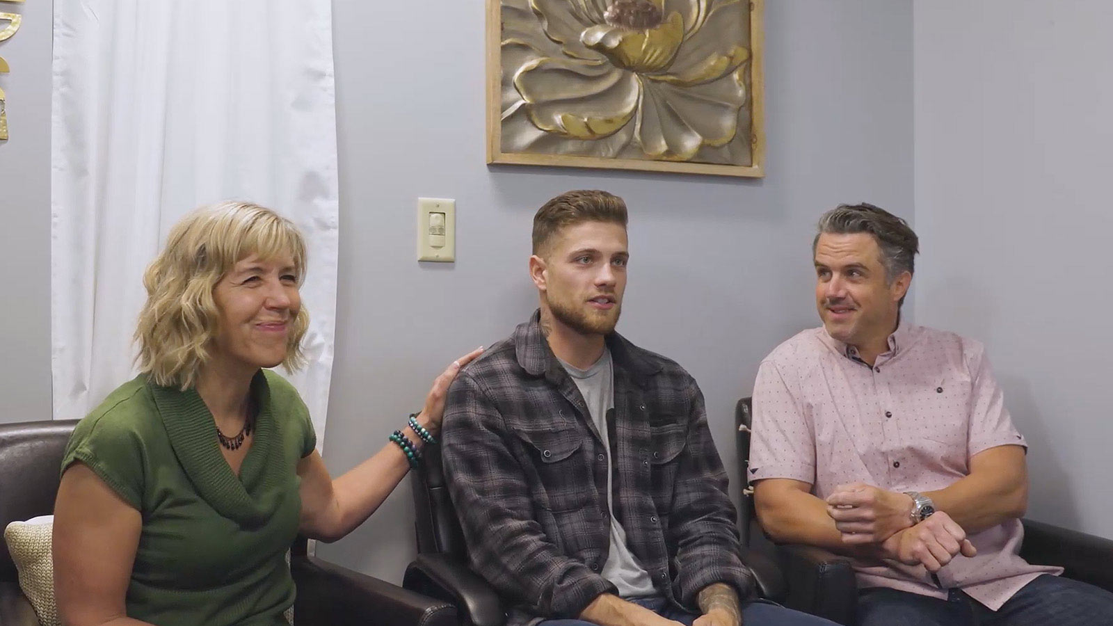 there are three people sitting on a couch talking to each other