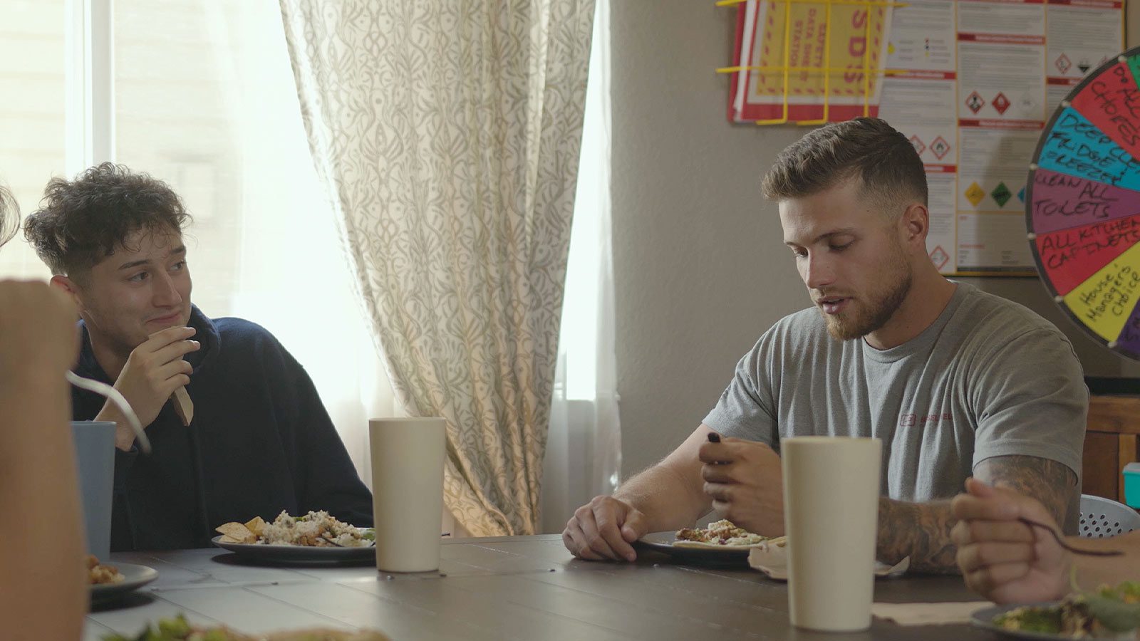 Two people sharing a meal and conversation at a wooden dining table.