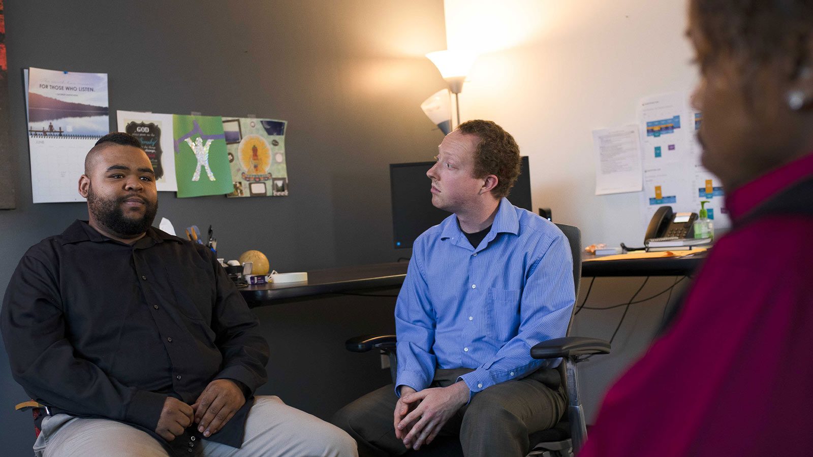 there are two men sitting in a chair talking to each other