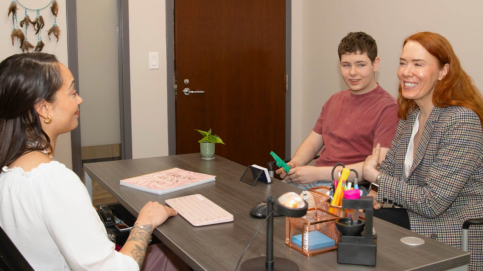 there are three people sitting at a table talking to each other