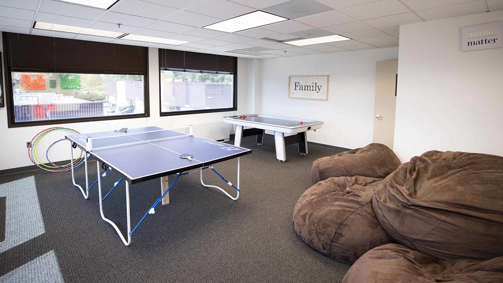 A recreational area with a ping pong table, air hockey table, and oversized beanbag chairs.