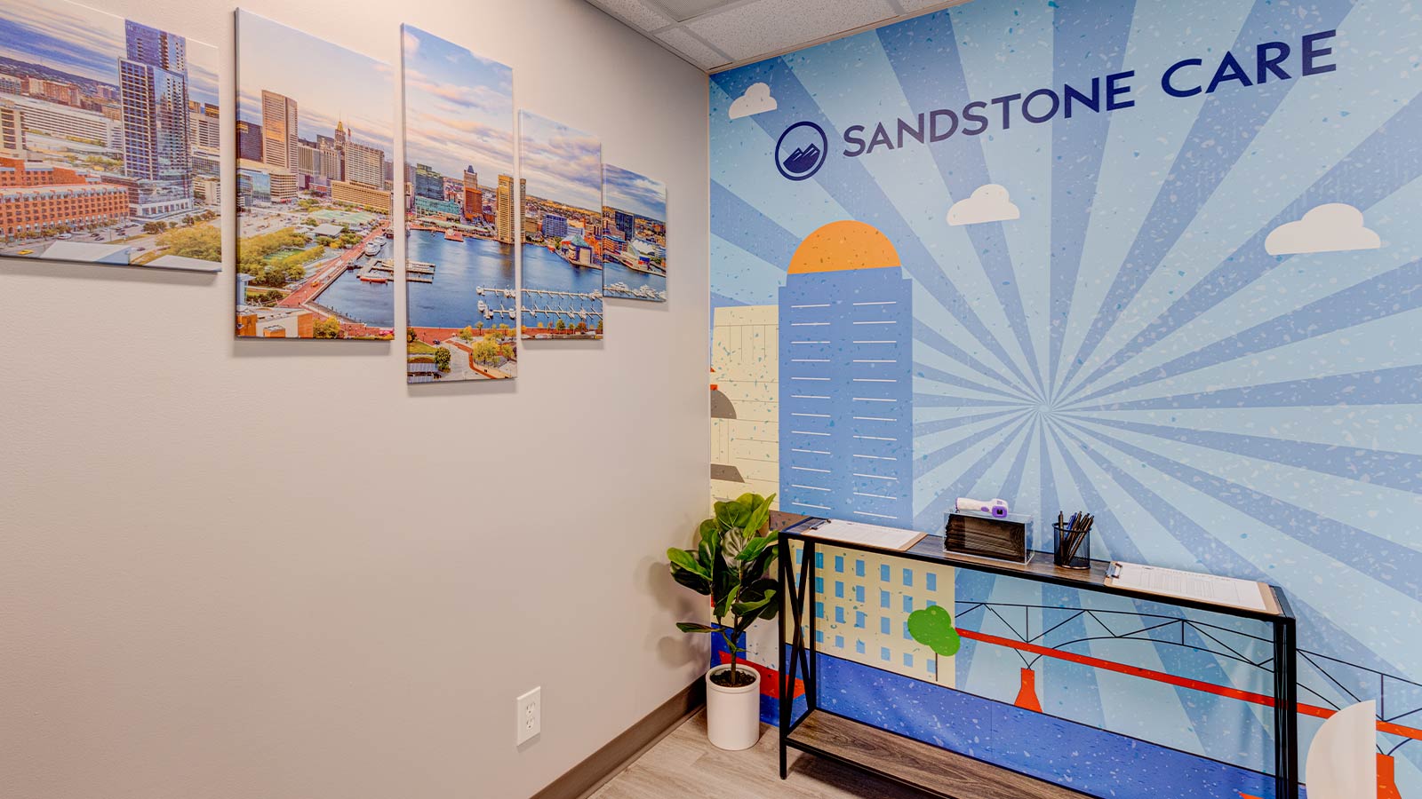A cheerful corner of an office decorated with a mural displaying the branding "SANDSTONE CARE" prominently on the wall.