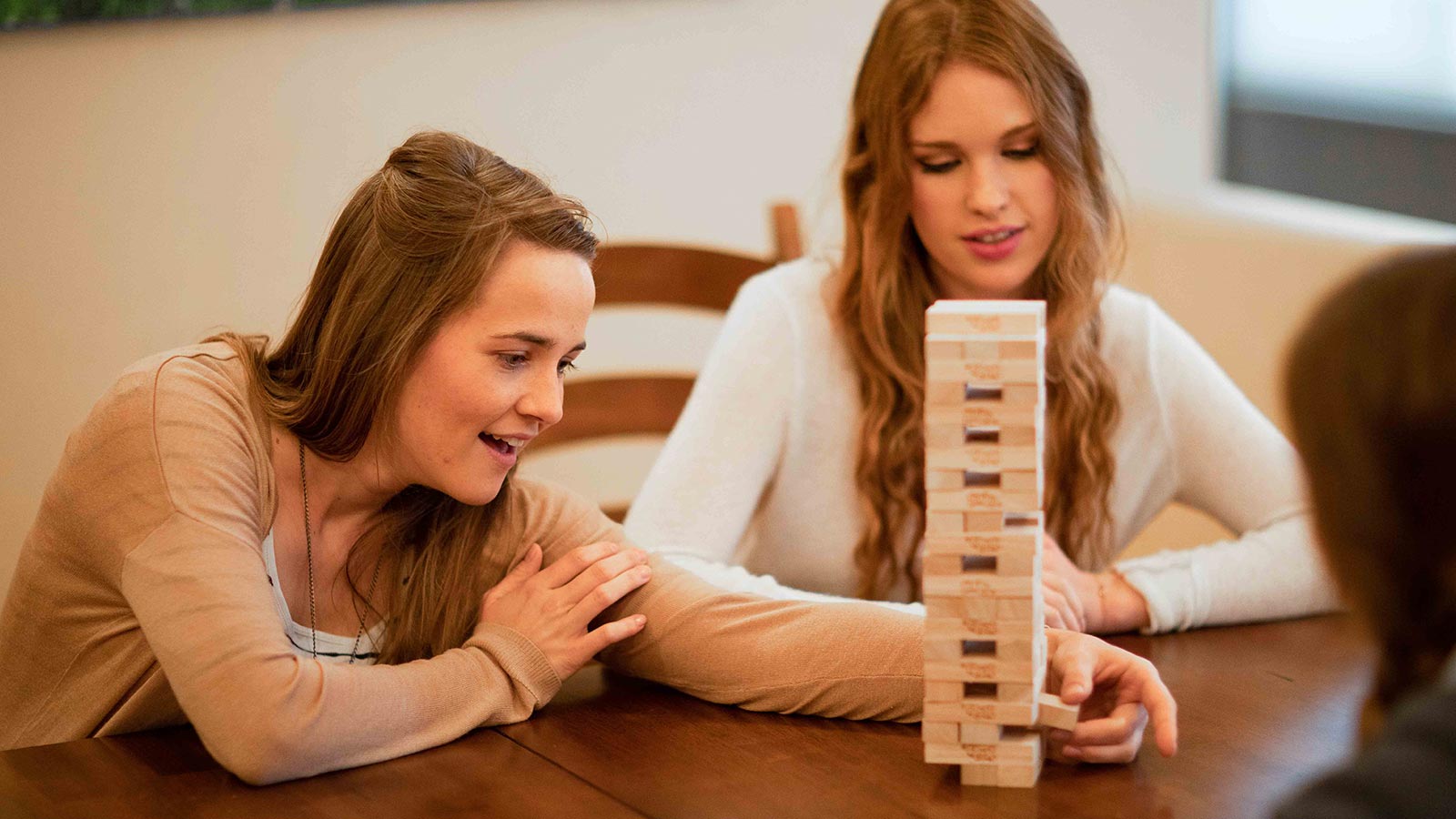A pair playing a careful game of Jenga on a wooden table.