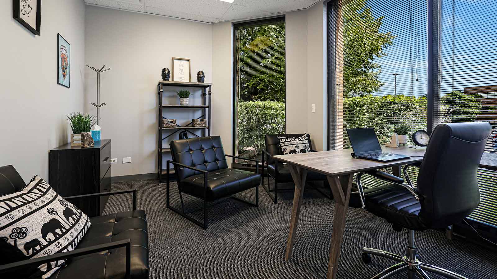 A professional office setting with modern furniture and a large window revealing outdoor greenery.