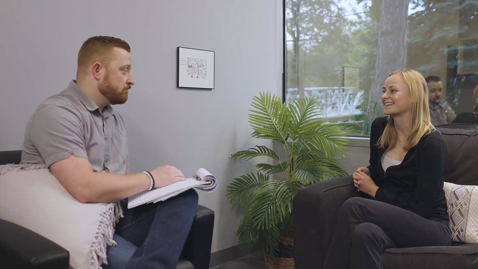 A therapy session with a professional discussing with a young woman in a cozy room.