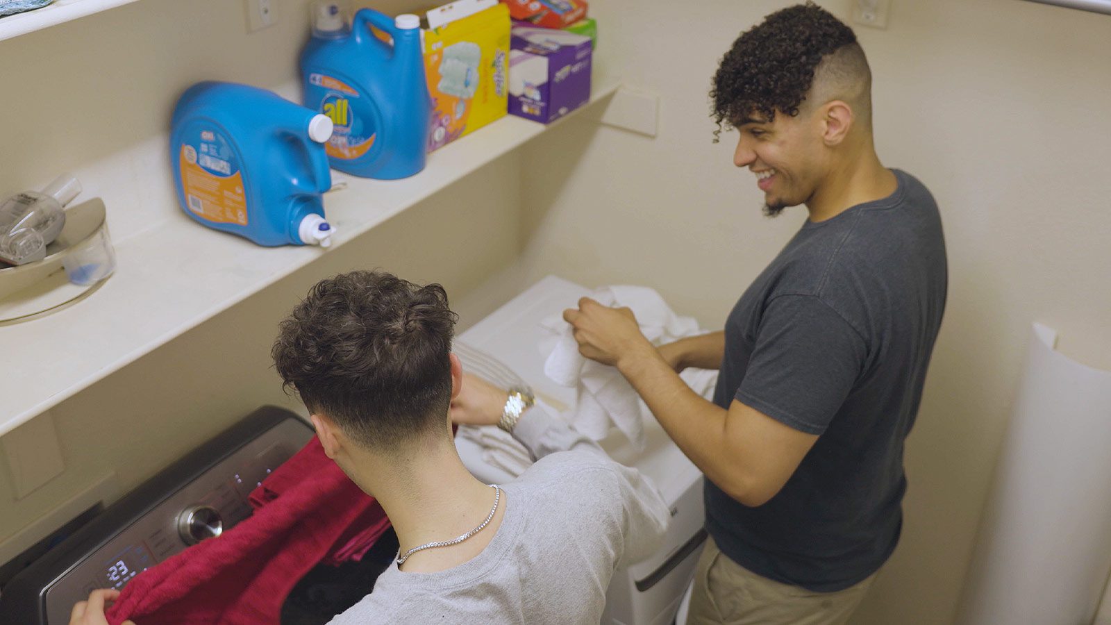 Two men laughing while doing laundry.