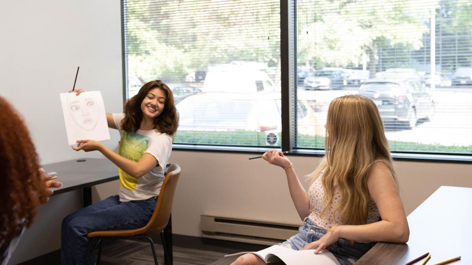 A creative group session where a person is showing a drawing to the class.