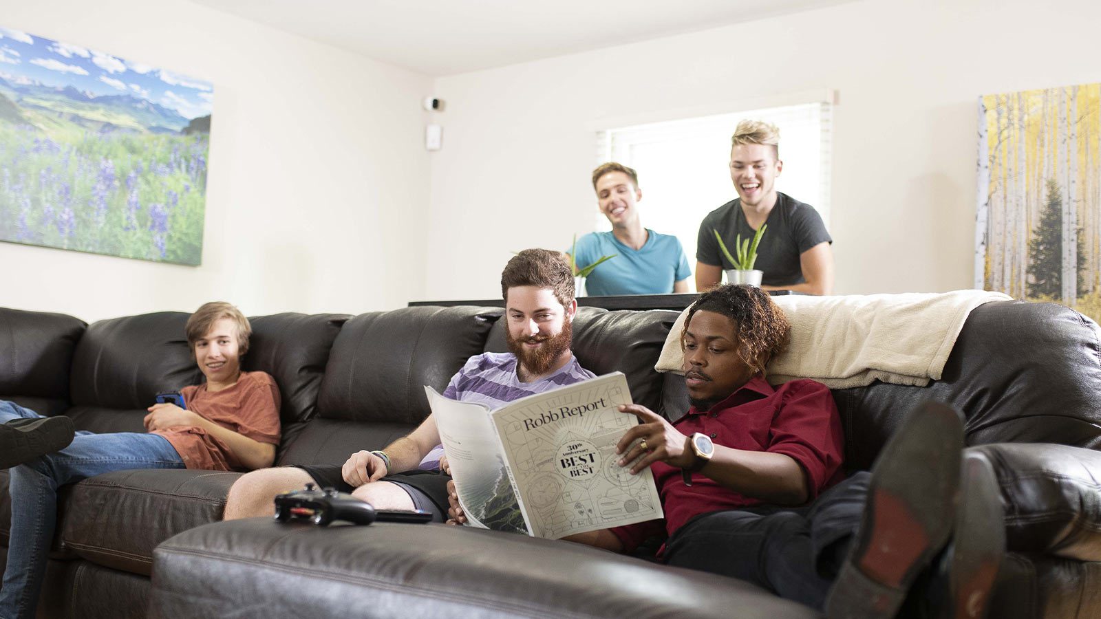 A group of men lounging on a couch, reading a newspaper and enjoying each other's company.