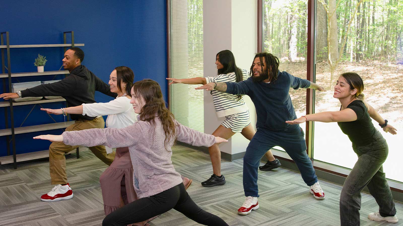 several people are practicing yoga in a room with a large window